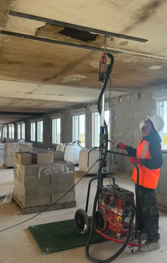 Compagnon utilisant le chariot Perc'height de Sept Tools pour percer un plafond, perforateur maintenu par le support du mât.