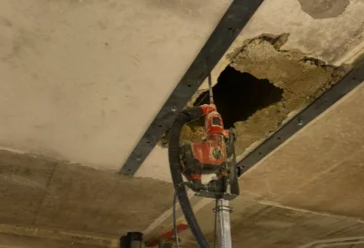 Gros plan du mât télescopique du chariot Perc'height, avec le support de perforateur, sous le plafond.
